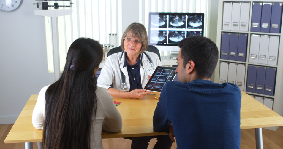 Doctor Talking To Interracial-Couples About Medical Findings