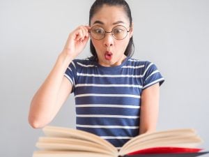 woman with wearing eye glasses got a surprised idea from the book.