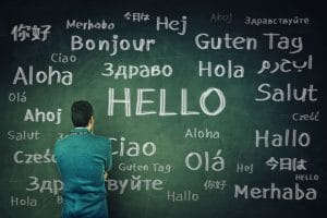businessman in front of a huge chalkboard written with the word hello in different languages.