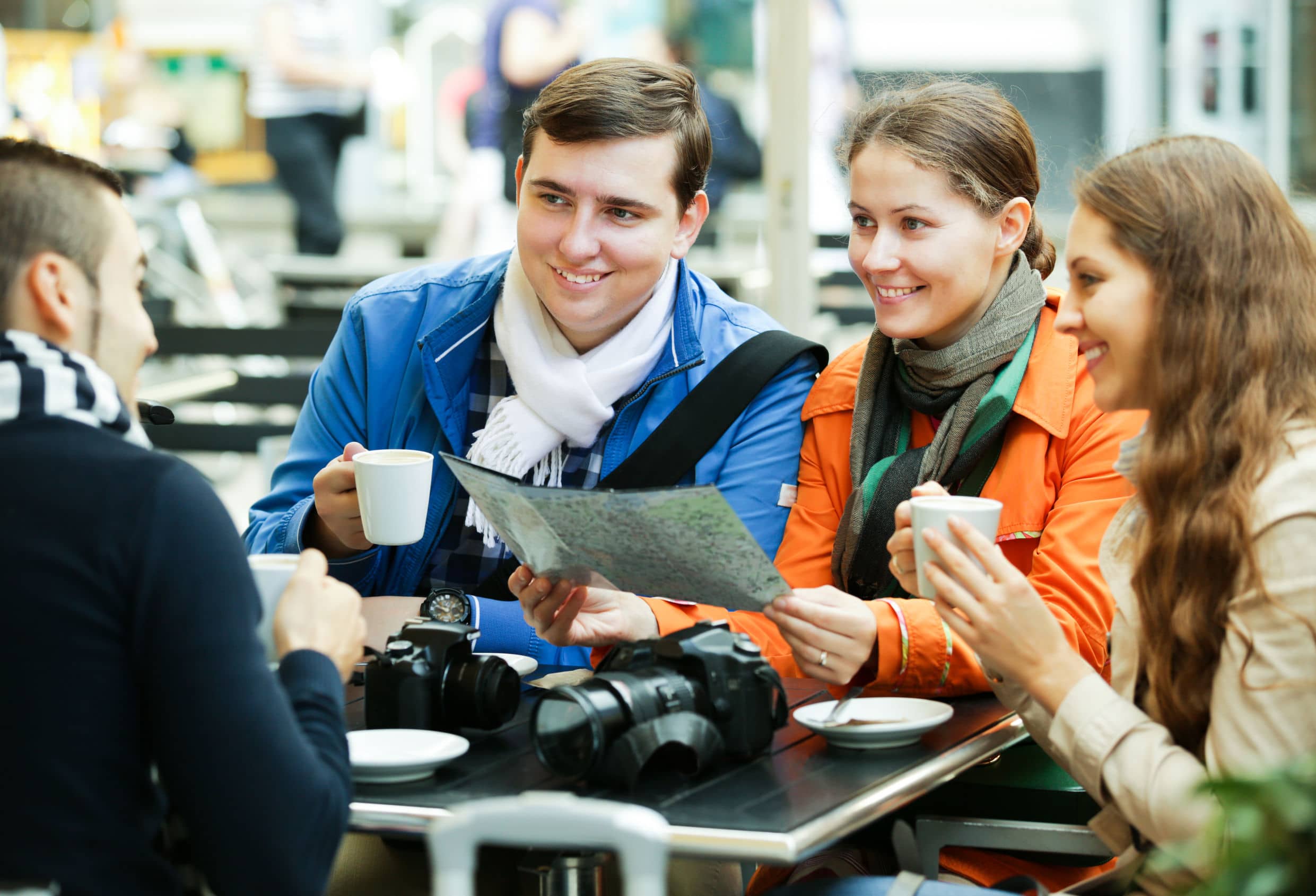 friends looking at a map outdoors while drinking coffee