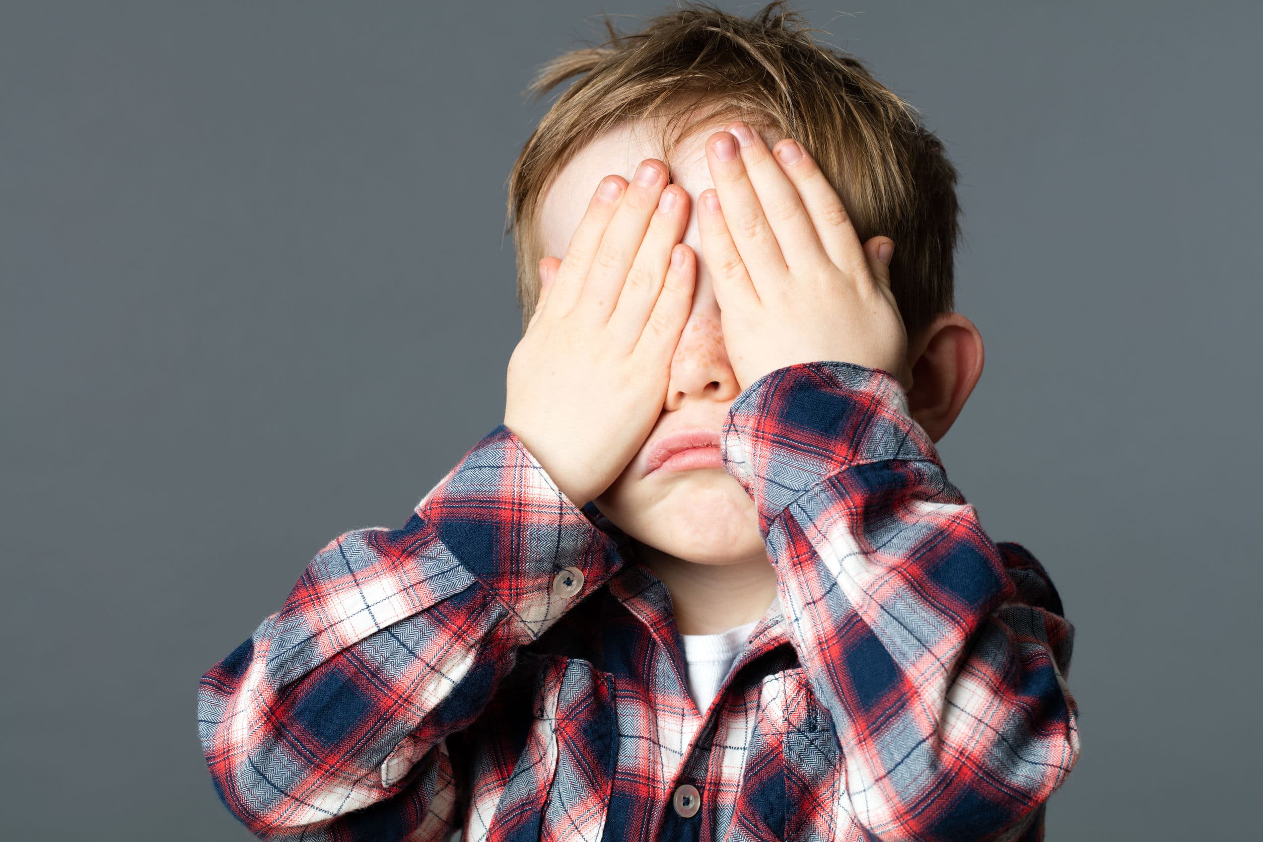 young child covering his eyes playing peekaboo