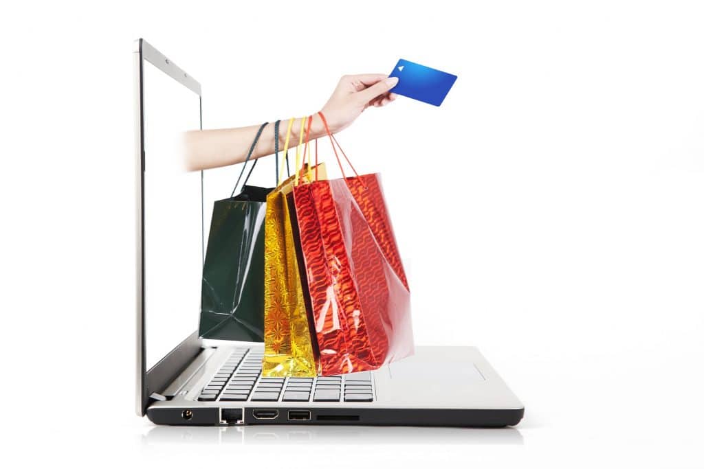 Hand holding credit card and shopping bag from laptop computer