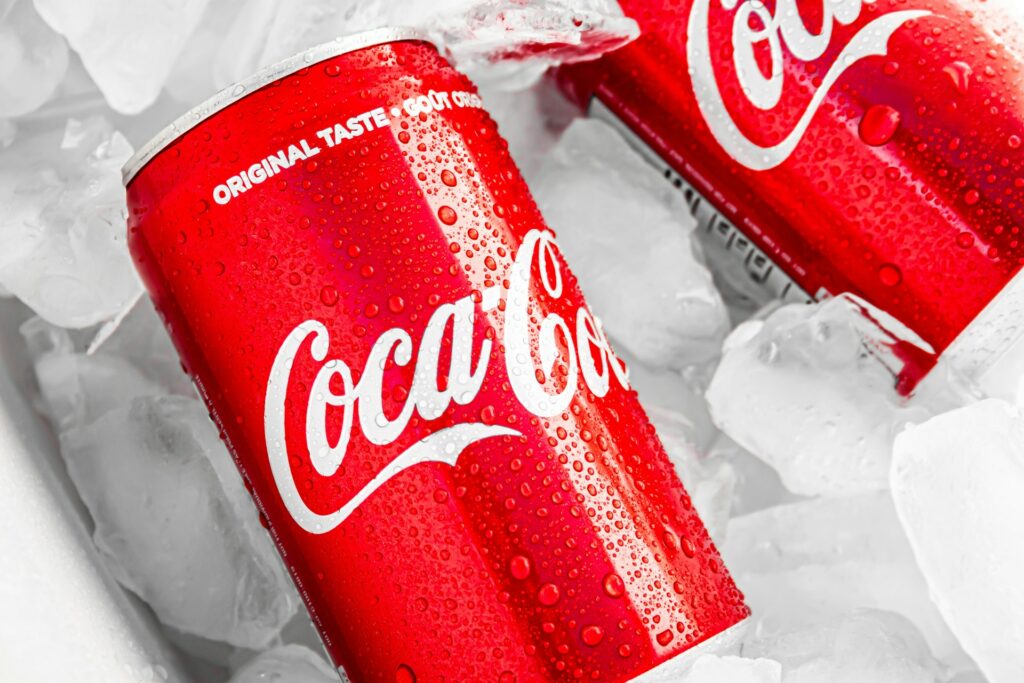 Two Coca-Cola cans in an ice bucket with condensation on them